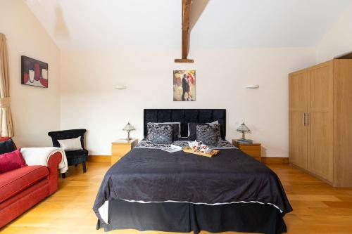 a bedroom with a bed and a red couch at Blackberry Barn in Wotton-under-Edge