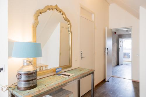 a dressing table with a mirror and a lamp on it at Hotel De Walvisvaarder in Lies