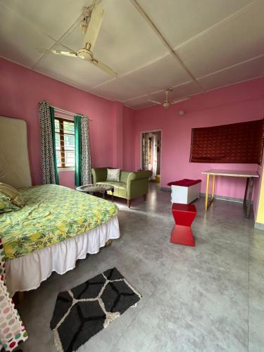 a bedroom with pink walls and a bed and a couch at Luna's Solace-The Rustic Stay-Ease in Guwahati