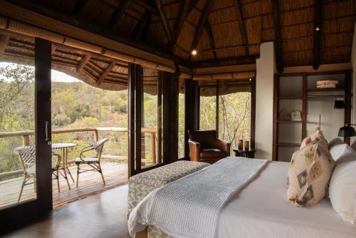 a bedroom with a bed and a balcony with a table at Tshwene Lodge in Vaalwater