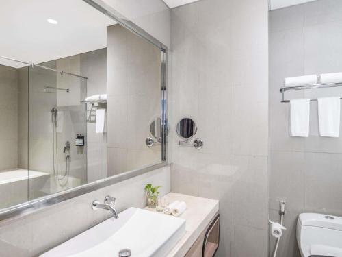 a white bathroom with a sink and a mirror at Mercure Jayapura in Jayapura