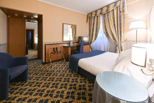 a hotel room with a bed and a desk at Hotel L'Aquila in Pomezia
