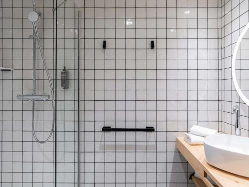 a white tiled bathroom with a shower and a sink at Ibis Styles Rouen Centre Rive Gauche in Rouen