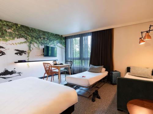 a hotel room with two beds and a table at Ibis Styles Rouen Centre Rive Gauche in Rouen