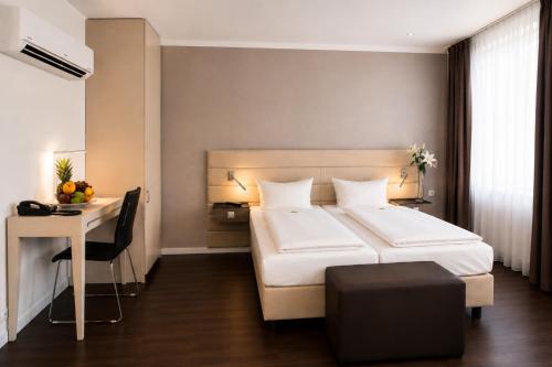 a hotel room with a bed and a desk and a bed and a table at Manhattan Hotel in Frankfurt