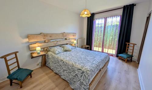 a bedroom with a bed and two chairs and a window at Maison du cèdre in Bonnac-la-Côte