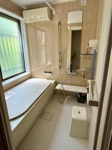 a bathroom with a tub and a sink and a window at Guest house AZSINN in Ueda