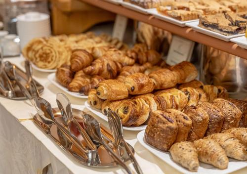 a bunch of pastries and croissants on plates in a bakery at Adler ApartHotel in Moena