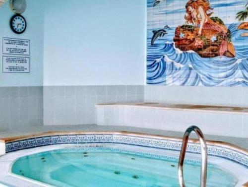 a hot tub in a bathroom with a painting of a mermaid at Apartamento Oásis Parque 3 in Portimão