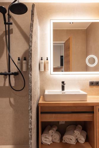 a bathroom with a sink and a mirror and towels at Aparthotel Maso Corto in Maso Corto