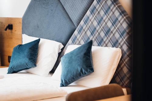 a bed with two blue pillows on top of it at Aparthotel Maso Corto in Maso Corto