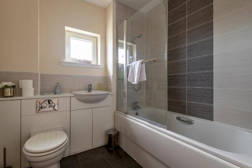 a bathroom with a toilet and a tub and a sink at The View, 22 School Park in Kingsbarns