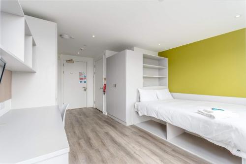 a bedroom with a white bed and a yellow wall at Modern Studios in Central Coventry in Coventry