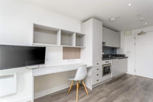 a white kitchen with a tv and a white chair at Modern Studios in Central Coventry in Coventry