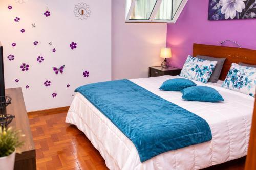 a bedroom with a bed with blue pillows and purple walls at Spot Matur Apartment in Machico