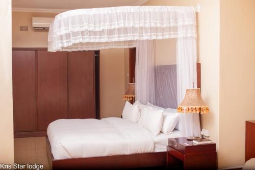 a bedroom with a white bed with a canopy at Kris Star Lodge in Blantyre