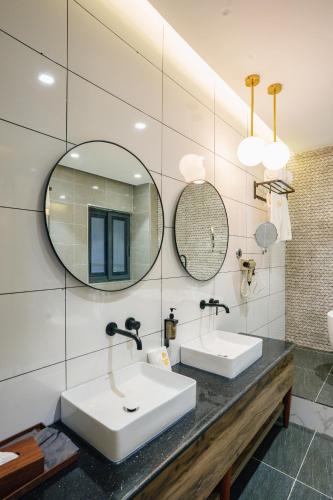 a bathroom with two sinks and two mirrors at Vora Addis Hotel in Addis Ababa