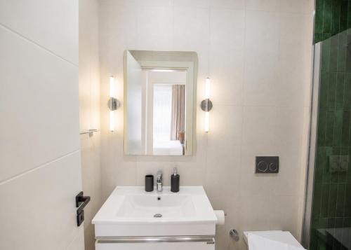 a white bathroom with a sink and a mirror at Abodos Aqualina D2/1 Fm in Vavilas