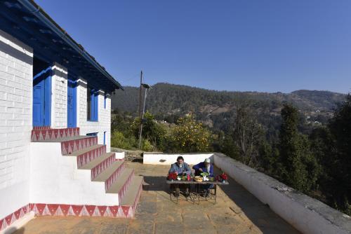 two people sitting at a table outside of a building at Idyllic Haven Heritage, Jageshwar in Jageshwar