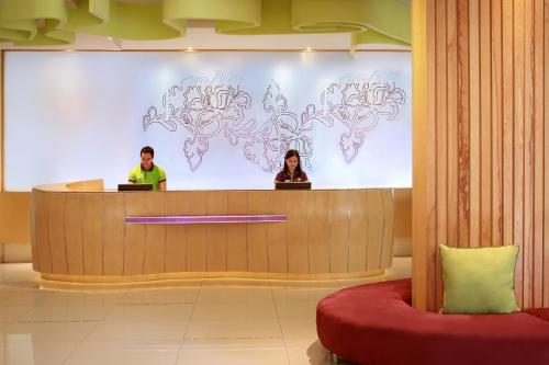 two people are sitting in front of a large screen tv at ibis Styles Yogyakarta in Yogyakarta