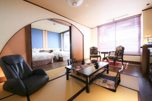 a living room with a mirror and a table and chairs at 旅館かわな -Ryokan Kawana- in Kimitsu