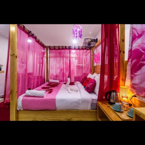 a bedroom with pink curtains and a large bed at DSR Pink Suites in Hyderabad