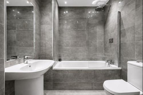 a bathroom with a tub and a sink and a toilet at Roomspace Serviced Apartments - Nouvelle House in Sutton