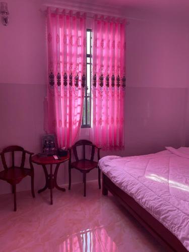 a bedroom with pink curtains and a bed and a window at Khách Sạn Thành Châu 2 