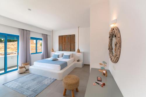 una camera da letto bianca con un letto e una sedia di Lindos Portes Suites - Adults Only a Líndos
