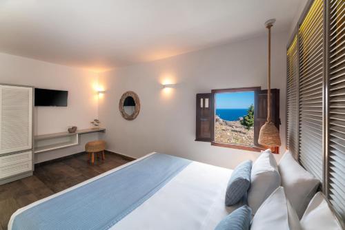 a bedroom with a large bed and a window at Lindos Del Mar Suites - Adults Only in Lindos
