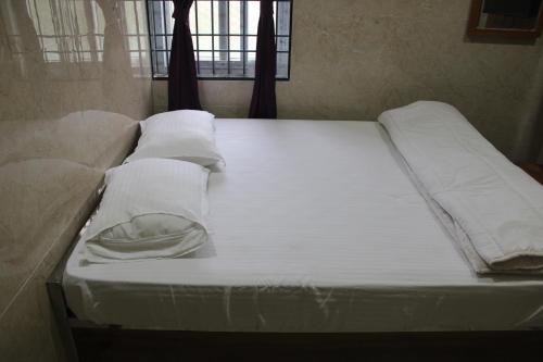 a large bed with white sheets and pillows on it at Srivari Lodge in Arcot