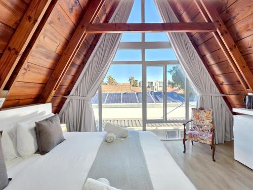 a bedroom with a white bed and a large window at Salt Boutique Guest House in Bloubergstrand