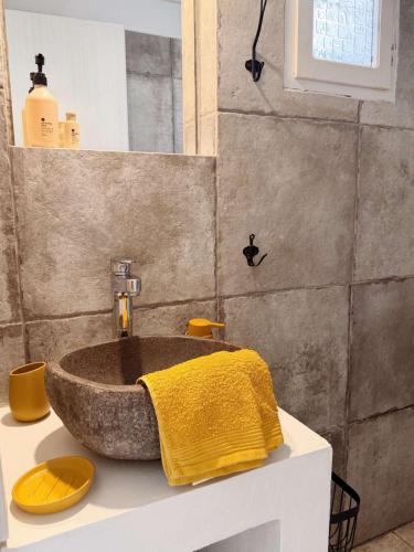 a bathroom with a stone sink with a yellow towel at Zacharias Seaside Studio Kimolos in Kimolos