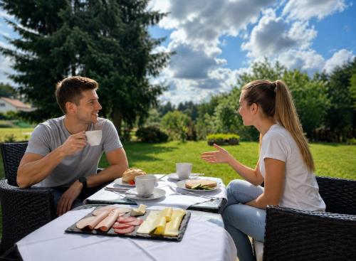 a man and a woman sitting at a table with food at MorNight in Spiegelau