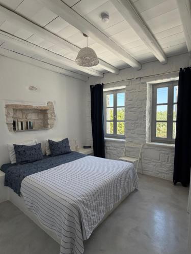 a bedroom with a large bed and two windows at LA MAISON D'HELENE in Naousa