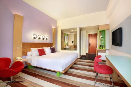 a bedroom with a white bed and a red chair at ibis Styles Yogyakarta in Yogyakarta