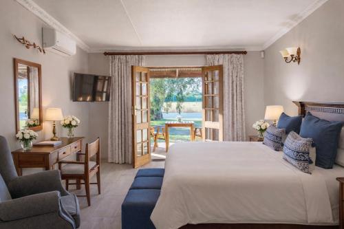 a bedroom with a bed and a desk and a chair at Bakenskraal Ostrich Palace in Oudtshoorn