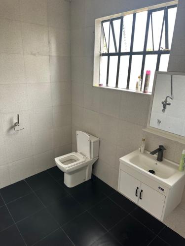 a white bathroom with a toilet and a sink at Bella Pollito in Nairobi