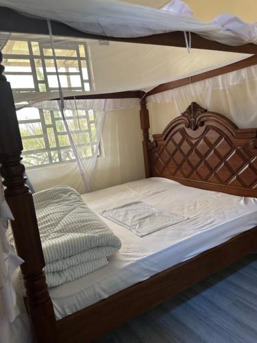 a bed with a canopy bed with white sheets at Bella Pollito in Nairobi