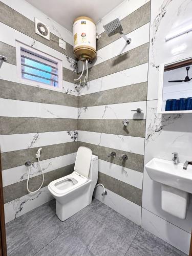 a bathroom with a toilet and a sink at Aura Suites Chernallur in Ernakulam