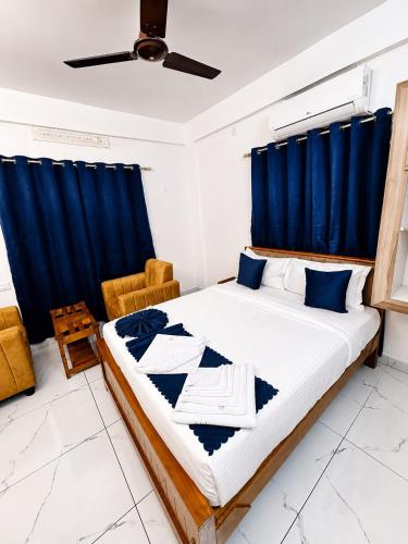 a bedroom with a large bed with blue curtains at Aura Suites Chernallur in Ernakulam
