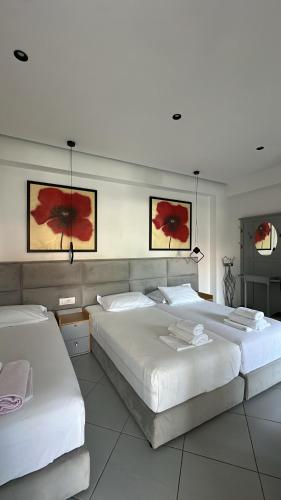 two beds in a bedroom with two red flowers on the wall at Vila Klea in Ksamil