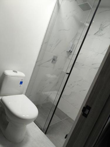 a bathroom with a toilet and a glass shower at Qantic Lodging & Rooftop in Medellín