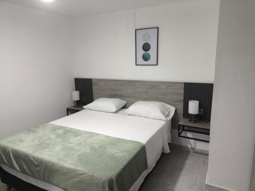 a bedroom with a large bed and two tables at Qantic Lodging & Rooftop in Medellín
