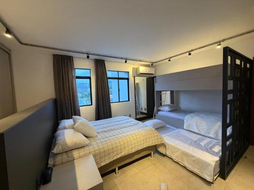 a bedroom with two beds and two windows at Cobertura Duplex Vista Cidade Centro TV4061 in Blumenau