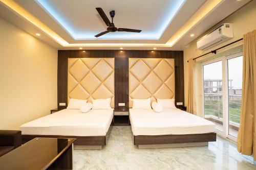 two beds in a room with a ceiling fan at Mahabhoj Hotel & Restaurant in Mandarmoni