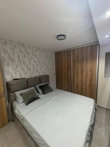 a bedroom with a large white bed with a wooden headboard at Omnia Lux Apartman 4C in Šabac