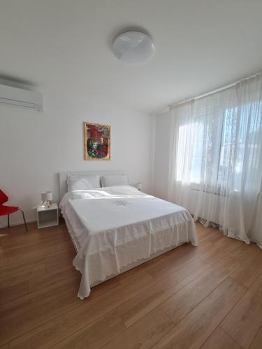 a white bedroom with a bed and a window at Casa Timavo in Ronchi dei Legionari