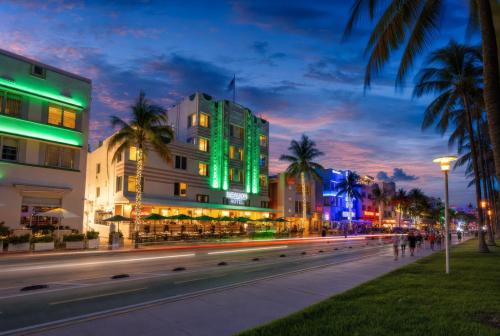 a city street with buildings and palm trees at night at Beacon South Beach Hotel in Miami Beach