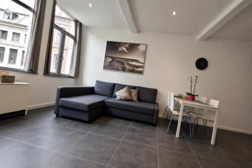 a living room with a couch and a table at Apart'Hotel Liège City Centre in Liège